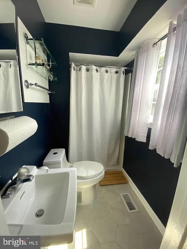 bathroom featuring tile patterned flooring, sink, curtained shower, and toilet