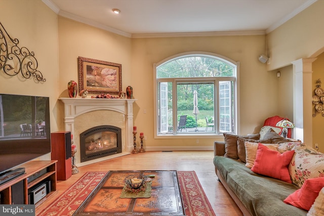 living room with light hardwood / wood-style floors, ornamental molding, and ornate columns