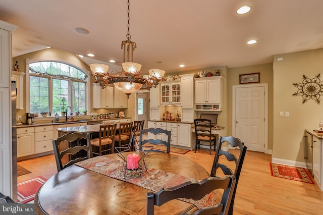 dining area with a notable chandelier, light hardwood / wood-style floors, and sink