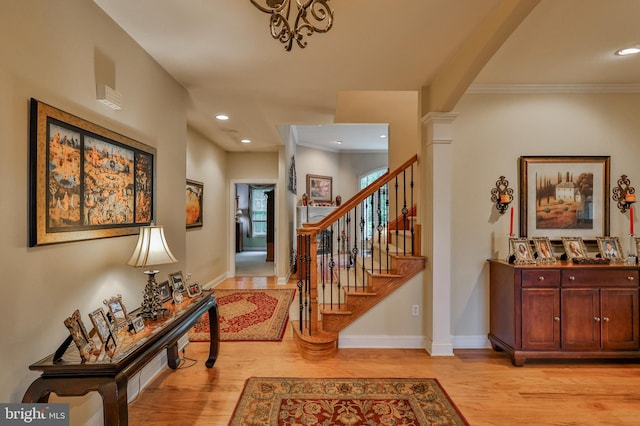 entrance foyer featuring light hardwood / wood-style floors, crown molding, and ornate columns