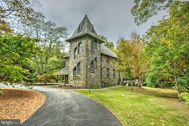 view of property exterior with central AC and a lawn