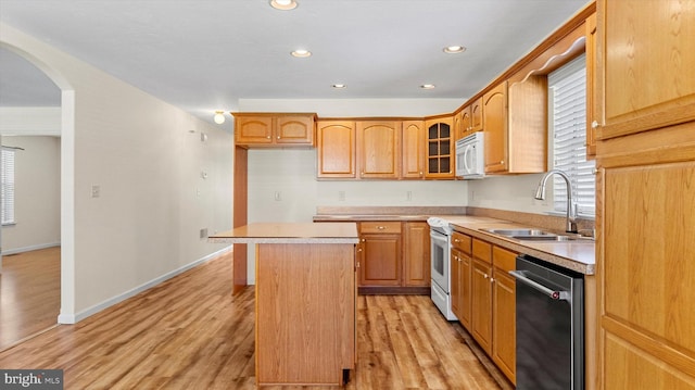 kitchen with white appliances, light hardwood / wood-style floors, a kitchen island, and sink