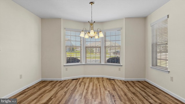 empty room featuring a notable chandelier and hardwood / wood-style flooring