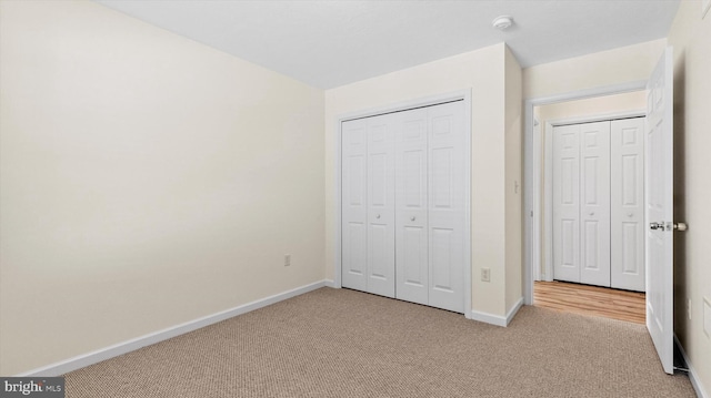 unfurnished bedroom with light colored carpet and a closet