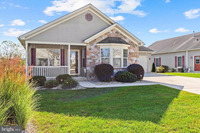 view of front of property featuring a front lawn, a garage, and covered porch