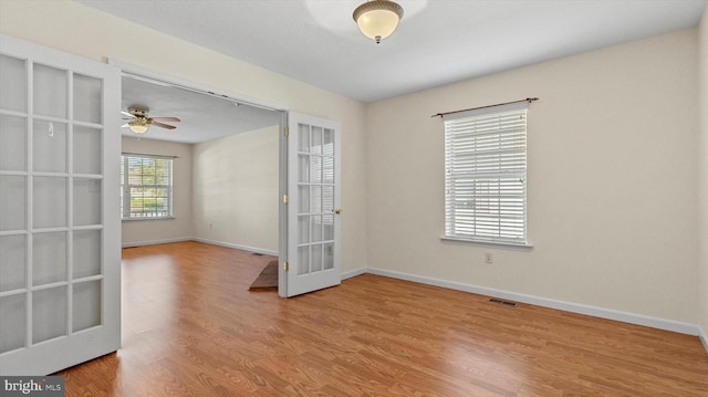 spare room featuring light wood-type flooring, ceiling fan, and french doors