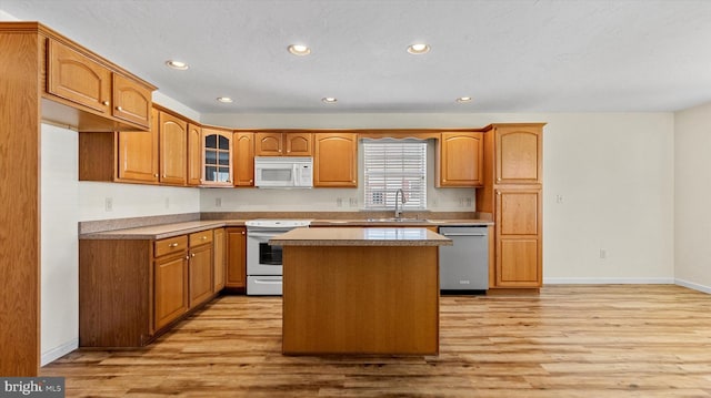 kitchen featuring a textured ceiling, sink, a kitchen island, light hardwood / wood-style flooring, and white appliances