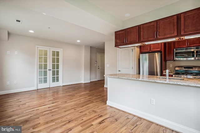 kitchen with light stone counters, sink, light hardwood / wood-style flooring, stainless steel appliances, and french doors