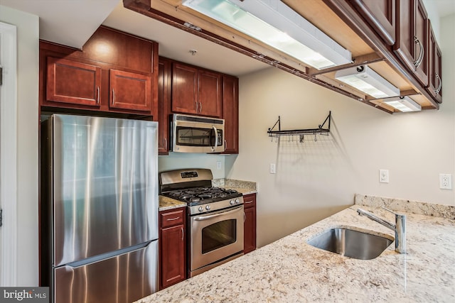 kitchen with light stone countertops, appliances with stainless steel finishes, and sink