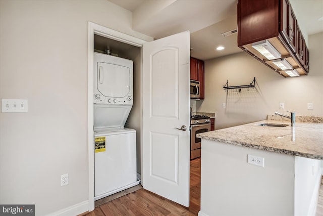 laundry area with stacked washer and dryer, sink, and light hardwood / wood-style flooring