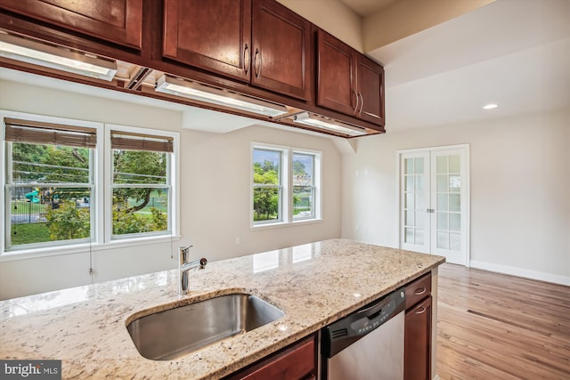 kitchen featuring light stone countertops, dishwasher, light hardwood / wood-style flooring, french doors, and sink