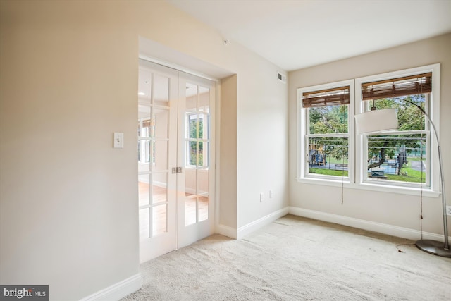 carpeted spare room featuring french doors