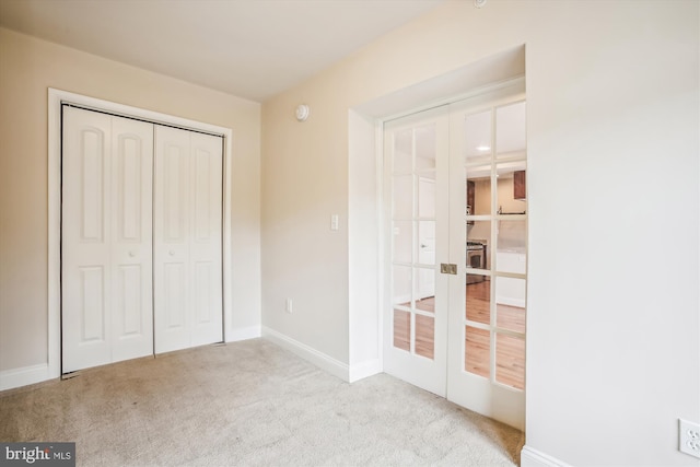 unfurnished bedroom featuring french doors, light colored carpet, and a closet