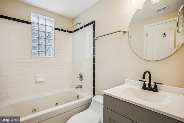 full bathroom with tiled shower / bath, vanity, and toilet