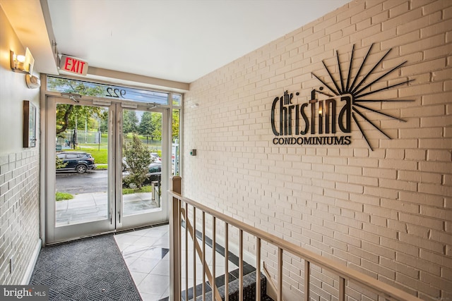 doorway to outside featuring brick wall and light tile patterned floors