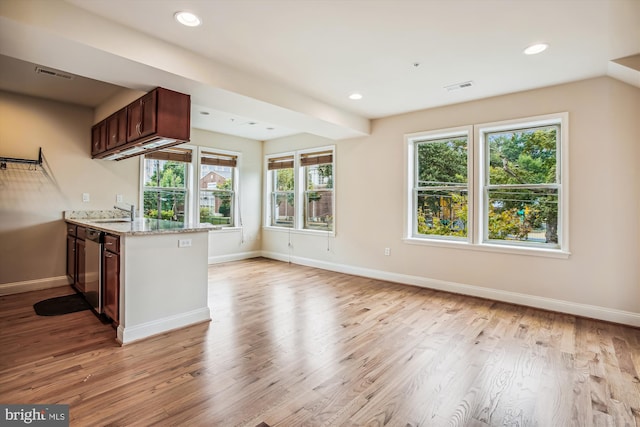 kitchen featuring light stone counters, sink, kitchen peninsula, stainless steel dishwasher, and light hardwood / wood-style floors