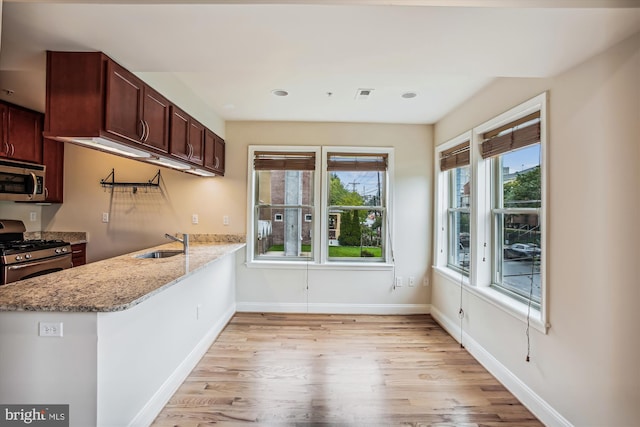 kitchen featuring light stone countertops, light hardwood / wood-style floors, sink, and stainless steel appliances