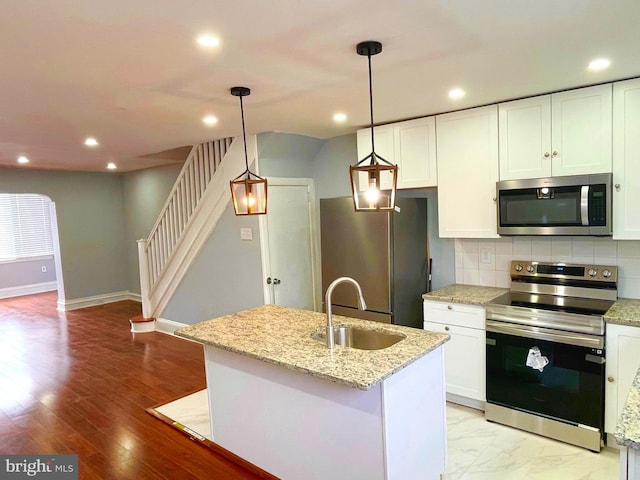 kitchen with hanging light fixtures, white cabinets, stainless steel appliances, and sink