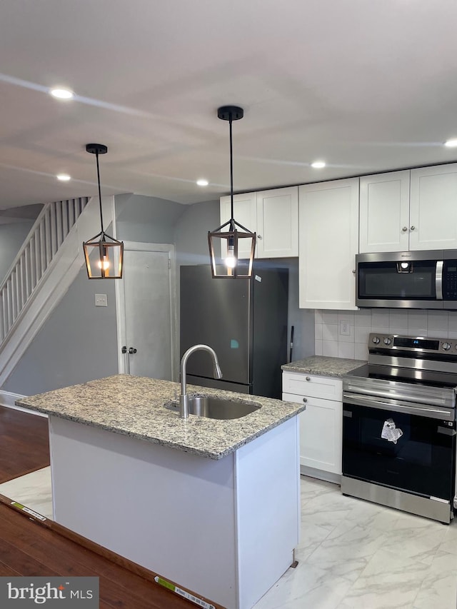 kitchen with a center island with sink, decorative light fixtures, and appliances with stainless steel finishes