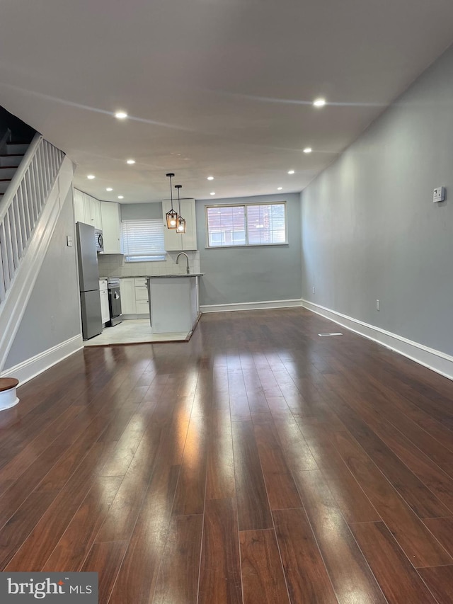 unfurnished living room with dark wood-type flooring and sink