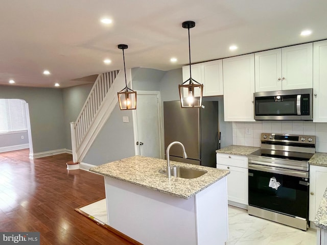 kitchen with white cabinetry, sink, hanging light fixtures, and appliances with stainless steel finishes