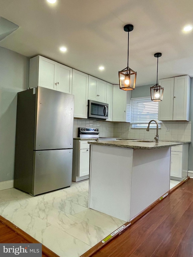 kitchen featuring appliances with stainless steel finishes, sink, pendant lighting, a center island, and white cabinetry