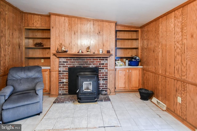 living room featuring wood walls, light tile patterned floors, a wood stove, and built in features