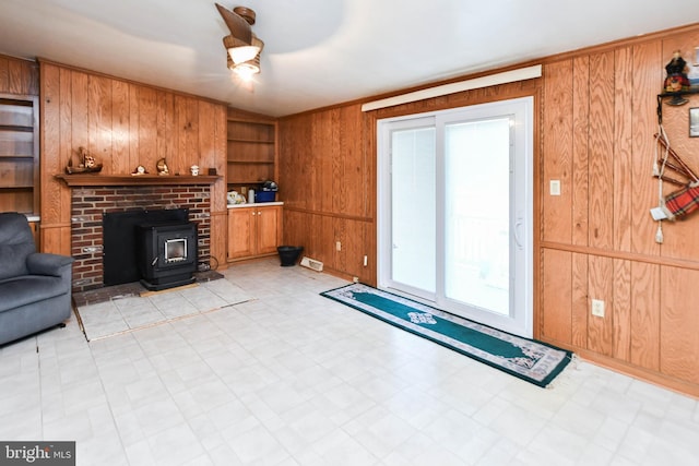 living room with built in shelves, wood walls, and a wood stove