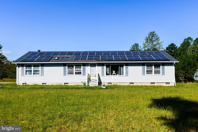 rear view of house featuring a lawn and solar panels