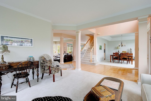 living room featuring crown molding, a chandelier, wood-type flooring, and decorative columns