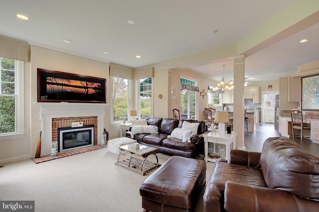 living room featuring a wealth of natural light, a chandelier, light carpet, and a fireplace