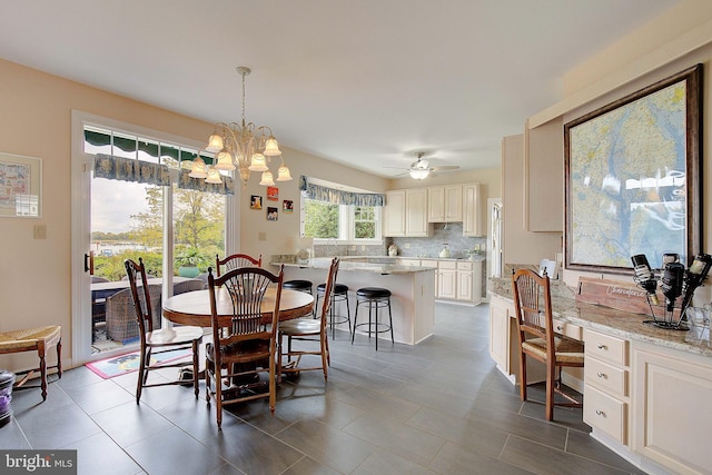 tiled dining room featuring ceiling fan with notable chandelier