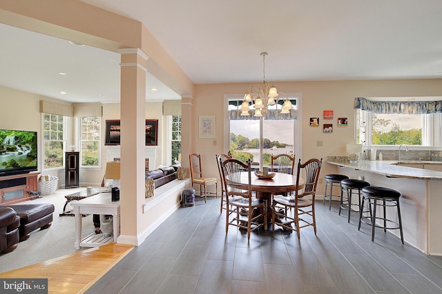 dining room with decorative columns, dark hardwood / wood-style flooring, a wealth of natural light, and an inviting chandelier