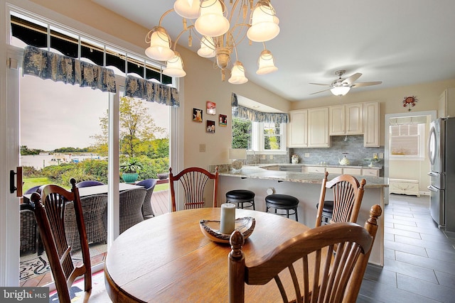 dining area featuring dark tile patterned flooring, sink, and ceiling fan with notable chandelier