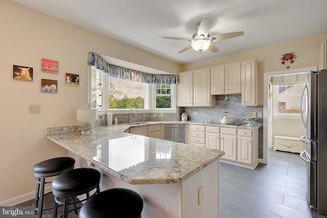 kitchen with tasteful backsplash, kitchen peninsula, a kitchen breakfast bar, stainless steel appliances, and light stone counters