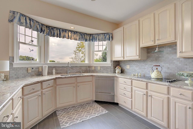 kitchen with black electric stovetop, dark tile patterned flooring, tasteful backsplash, sink, and light stone counters