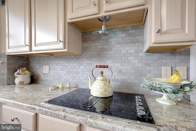 kitchen with black electric cooktop, light stone counters, and backsplash