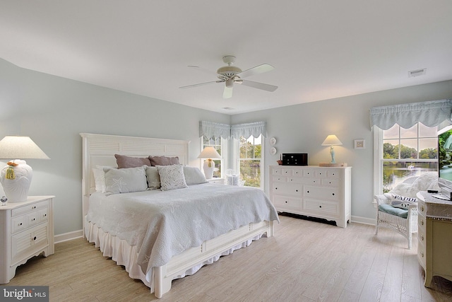 bedroom with ceiling fan, multiple windows, and light hardwood / wood-style floors