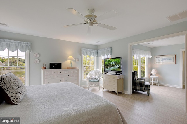 bedroom featuring light hardwood / wood-style flooring, ceiling fan, and multiple windows