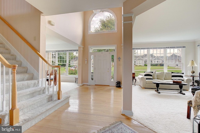 entrance foyer with a towering ceiling, a wealth of natural light, and light wood-type flooring