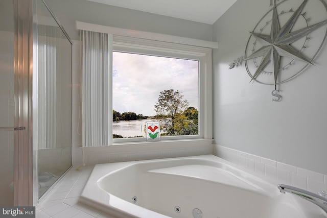 bathroom with a relaxing tiled tub and a water view