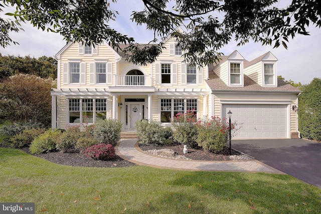 view of front of property with a front yard, a balcony, and a garage