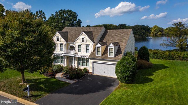 cape cod home featuring a garage, a front lawn, and a water view