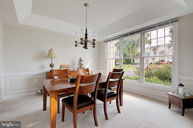 dining area featuring light carpet, a tray ceiling, and a wealth of natural light