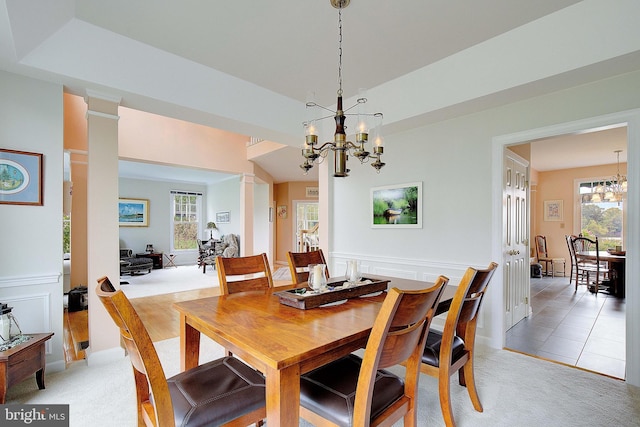 dining space with decorative columns, a healthy amount of sunlight, carpet flooring, and an inviting chandelier