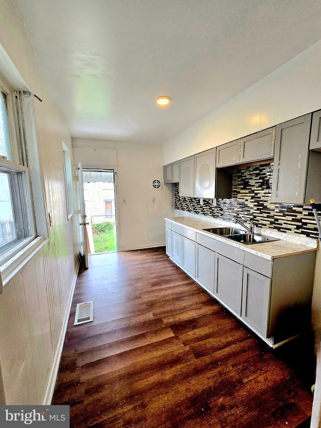 kitchen featuring backsplash, sink, dark hardwood / wood-style flooring, and gray cabinetry