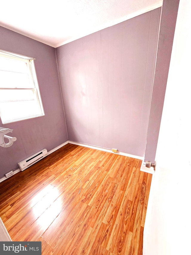 unfurnished room with a baseboard radiator, light hardwood / wood-style floors, and a textured ceiling