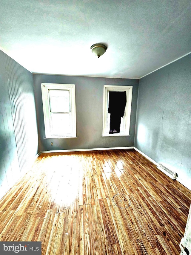 empty room featuring light wood-type flooring and a baseboard heating unit