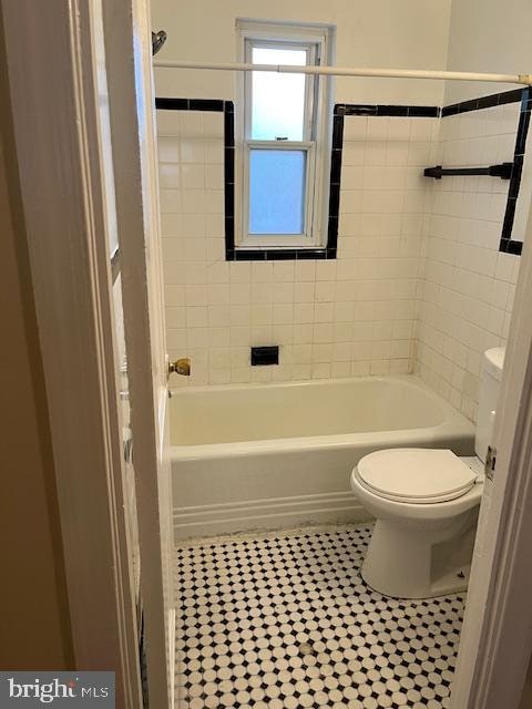 bathroom with tile patterned flooring, toilet, and tiled shower / bath combo