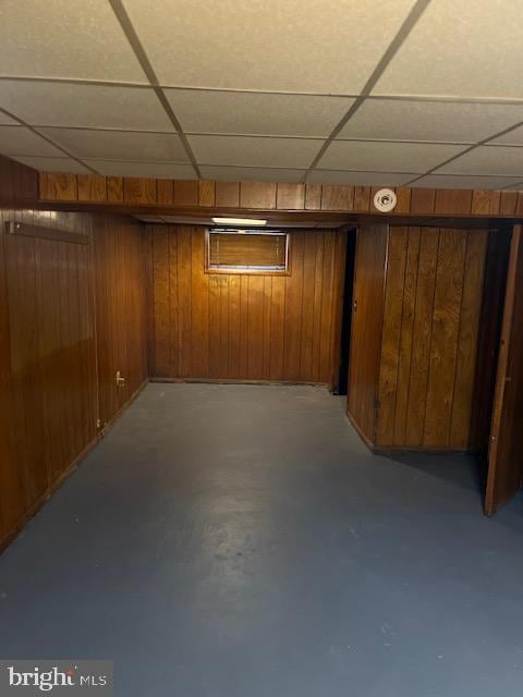 basement with wood walls and a paneled ceiling